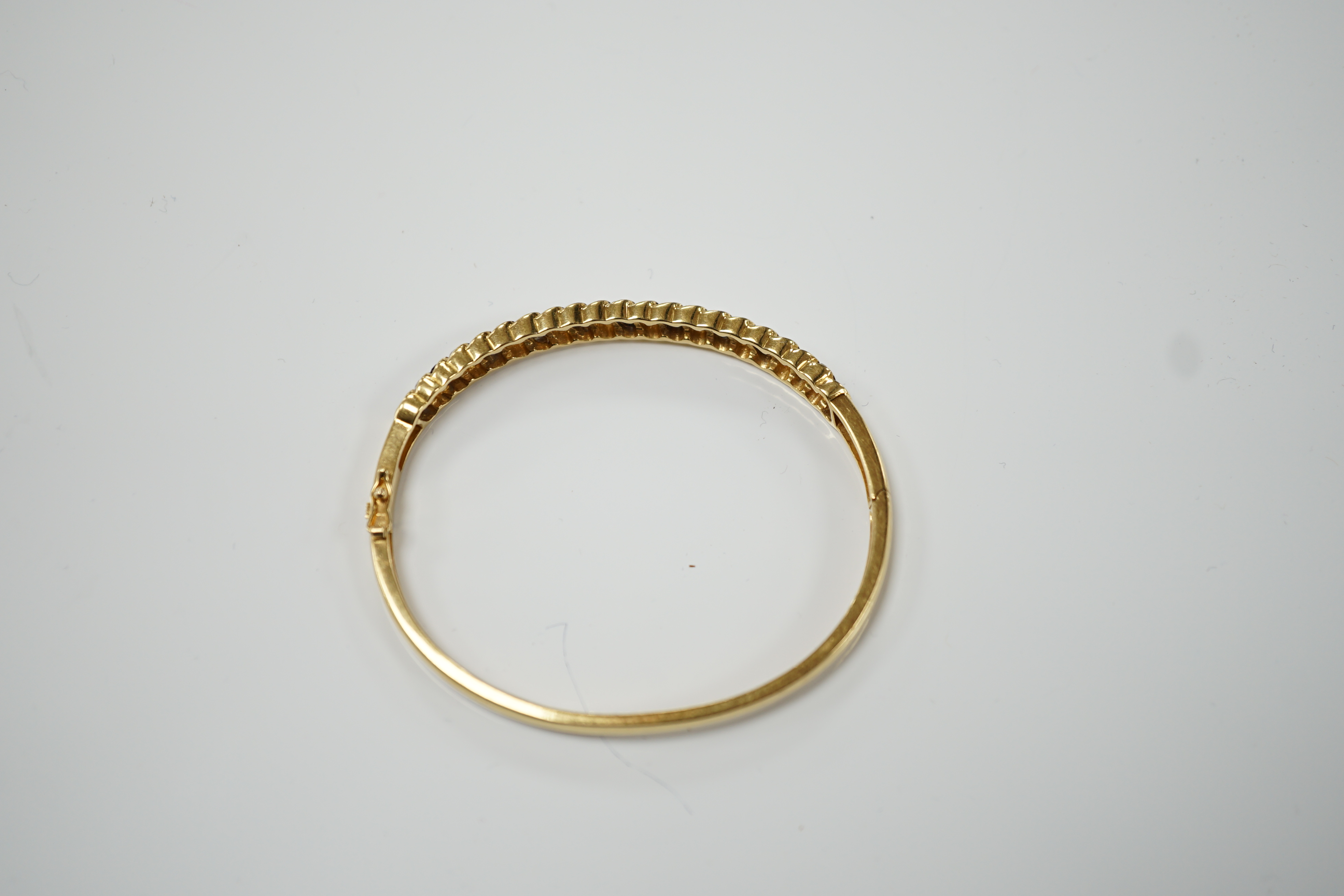 A 750 yellow metal, sapphire and diamond cluster set hinged bangle, interior diameter 56mm